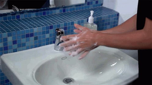a person with blue glove wiping up a white sink