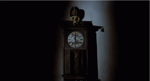an old fashioned black clock in a dark room