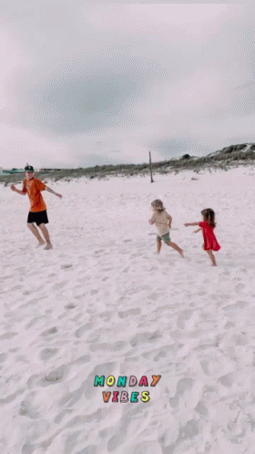 four people flying a kite while standing on sand