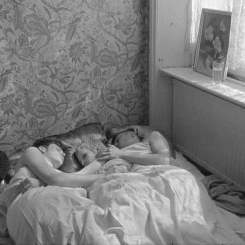 two women and a man are sleeping together