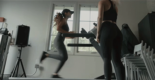 two woman in tight - fitting clothing walk down a treadmill