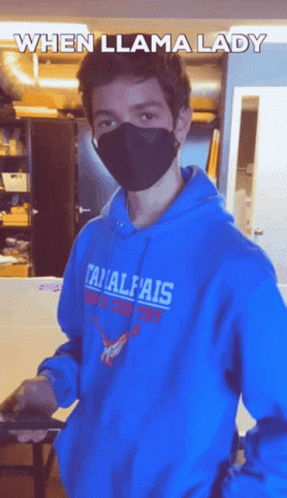a guy wearing an orange hoodie and face covering in an office
