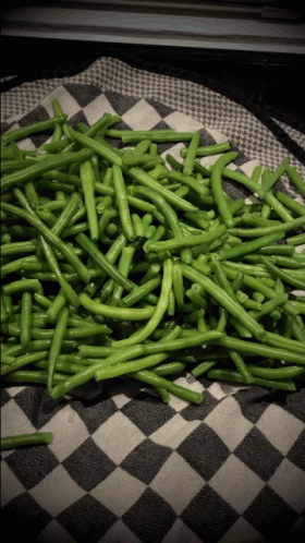 a pile of green string beans on a black and white checkered towel