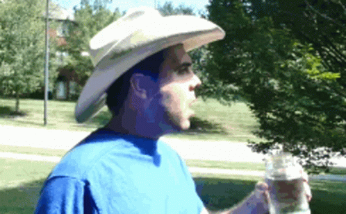a man wearing white make up and a hat with a water bottle