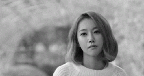 a young woman in a white sweater looking at the camera