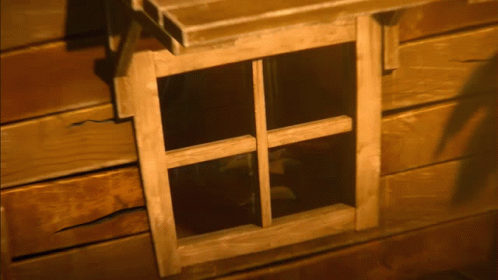 the window frame in a blue log house is open and some stuff is on the ground