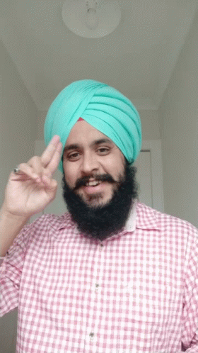 a man in a turban holding a peace sign up