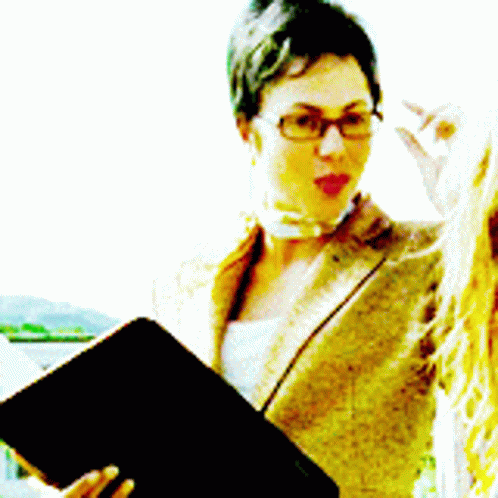 woman in glasses reading while holding up a large black book