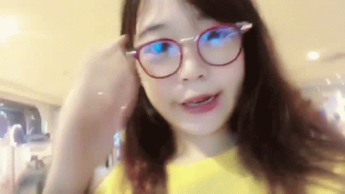 a girl with large yellow glasses holding her hair