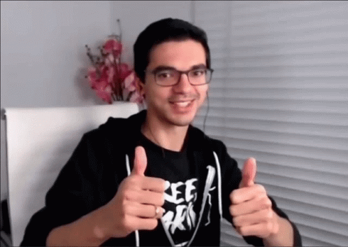 a man in glasses and a hoodie is giving the thumbs up sign