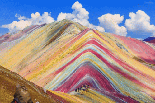 mountain side with rainbow colored hills in the sky