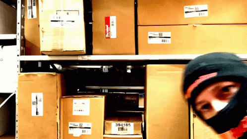 man wearing a ski mask in front of boxes of file