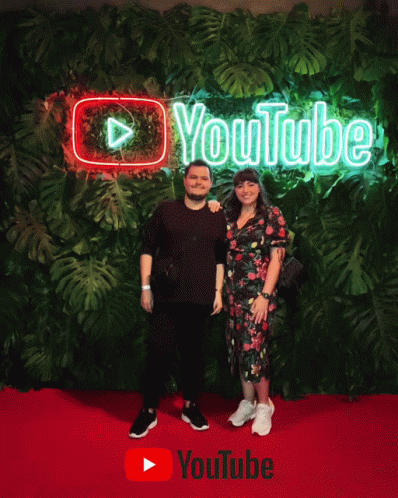 a man and woman standing in front of a large green wall