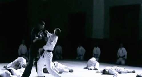 an open floor with people in white shirts and black pants doing karate moves