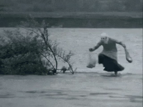 an old pograph of a person in the middle of the water on a surfboard
