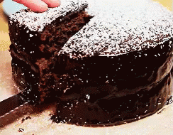 a large cake covered in powdered sugar with blue gloves