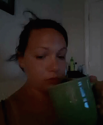 a woman holding a cup looking at her cell phone