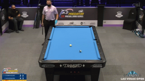 a man standing near a pool table in front of people