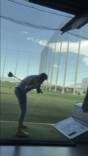 a woman in a white jacket is practicing golf