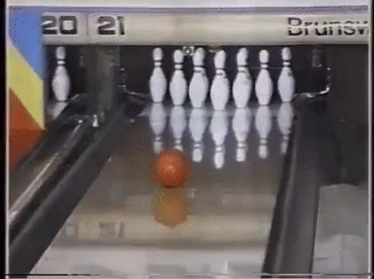 a blue ball that is about to fall on a bowling alley