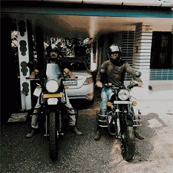two people sitting on motorcycles parked in a garage
