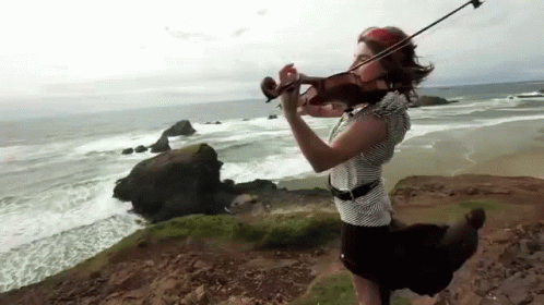 there is a person playing violin near the ocean