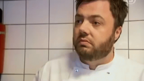 a man in a kitchen with a large beard and white shirt