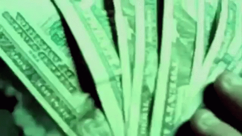 a man holding a bunch of money with green light