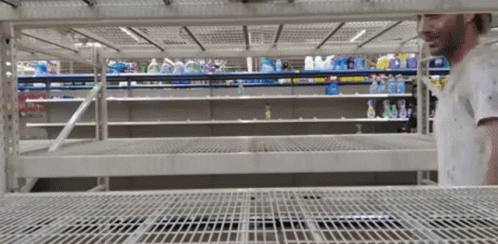a man looks up into the empty shelf in a supermarket
