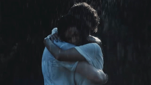 a woman hugging another woman standing in the rain