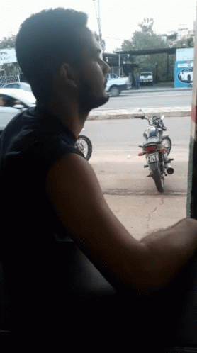 person looking out car window at motorbike parked on the street