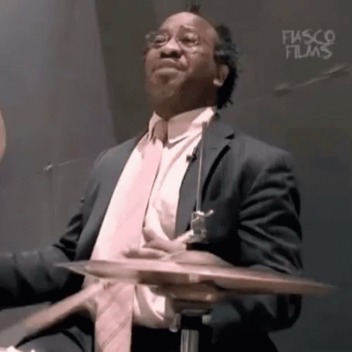 a man in a suit holding a drum kit