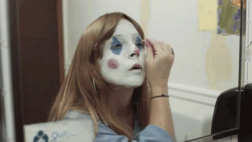 a woman with makeup on her face looking in a mirror