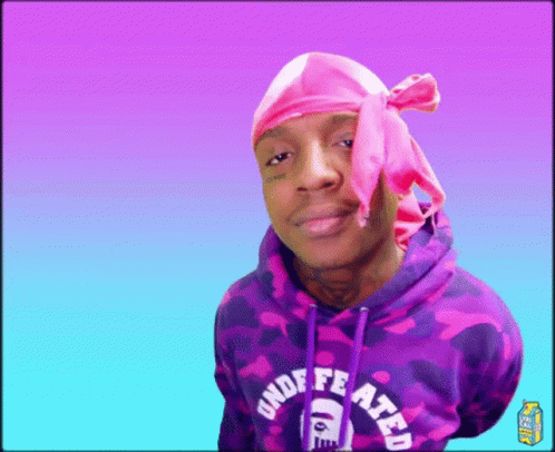 a young man wearing a purple sweatshirt with a pink headscarf