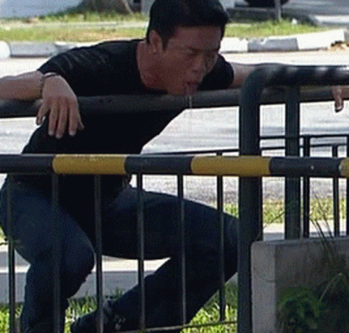 man in a black shirt on a bench, possibly leaning over