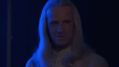 a man with long white hair standing in a room