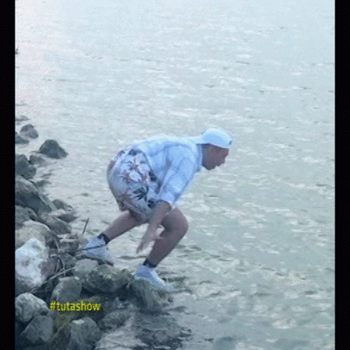 a person in yellow hat picking rocks off the shore