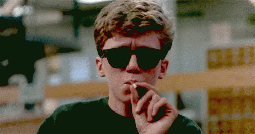 a young man wearing sunglasses has his hand in his mouth