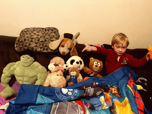 a little boy is playing on the couch with his stuffed animals
