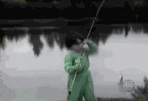 a young person standing on the shore with a fishing pole