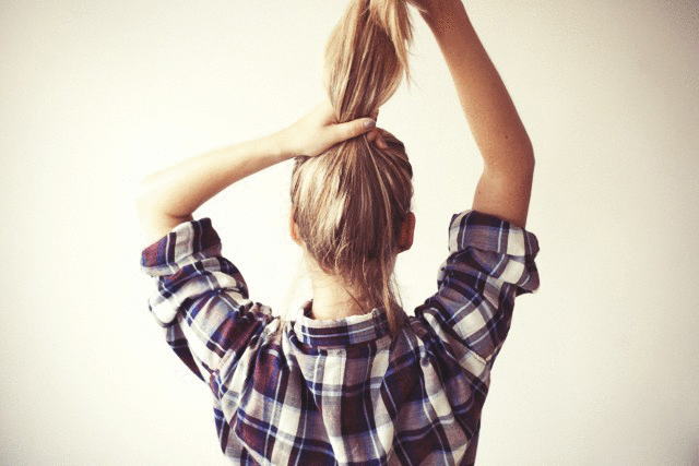 a woman standing up holding her hair in the air