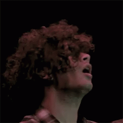 a man with curly hair standing in the dark