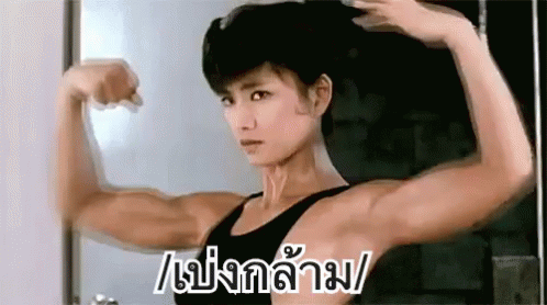 an asian woman flexing her muscles in the mirror