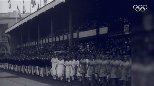 an old black and white po of a line of women wearing aprons at a baseball game