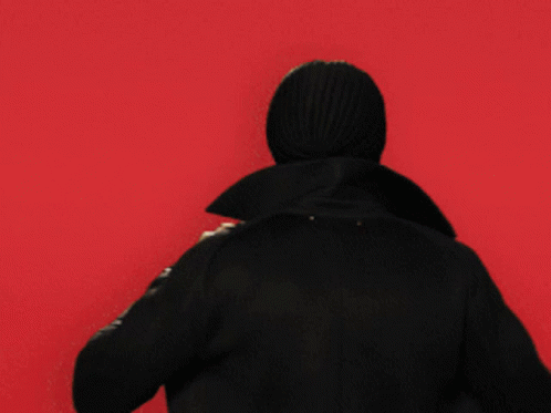 the back of the person, dressed in a black hoodie, stands alone