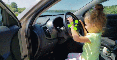 a little girl sitting inside of a car holding a steering wheel