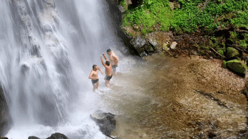 three people in blue suits walking towards a waterfall