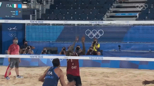 men in blue shirts are playing volleyball with people watching