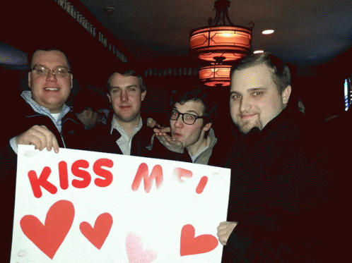 a group of men holding a white sign with hearts on it