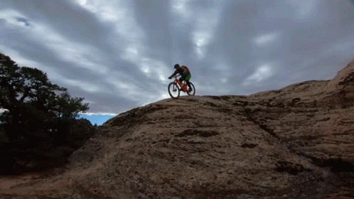 a guy riding a bike on top of a rock